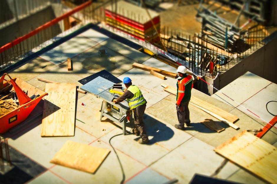 two male construction workers cutting wood on construction site.