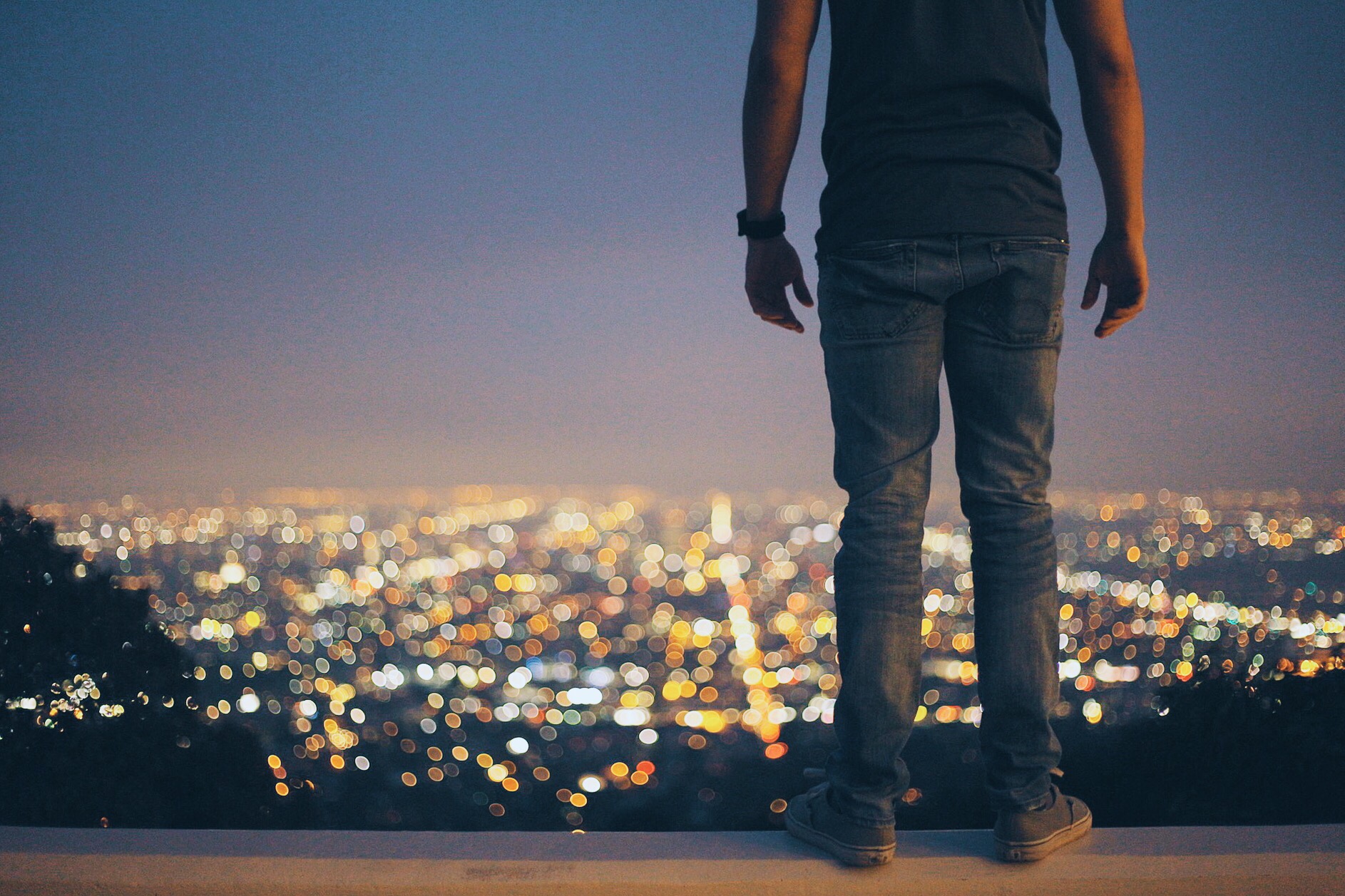 man standing looking at a city during nighttime.