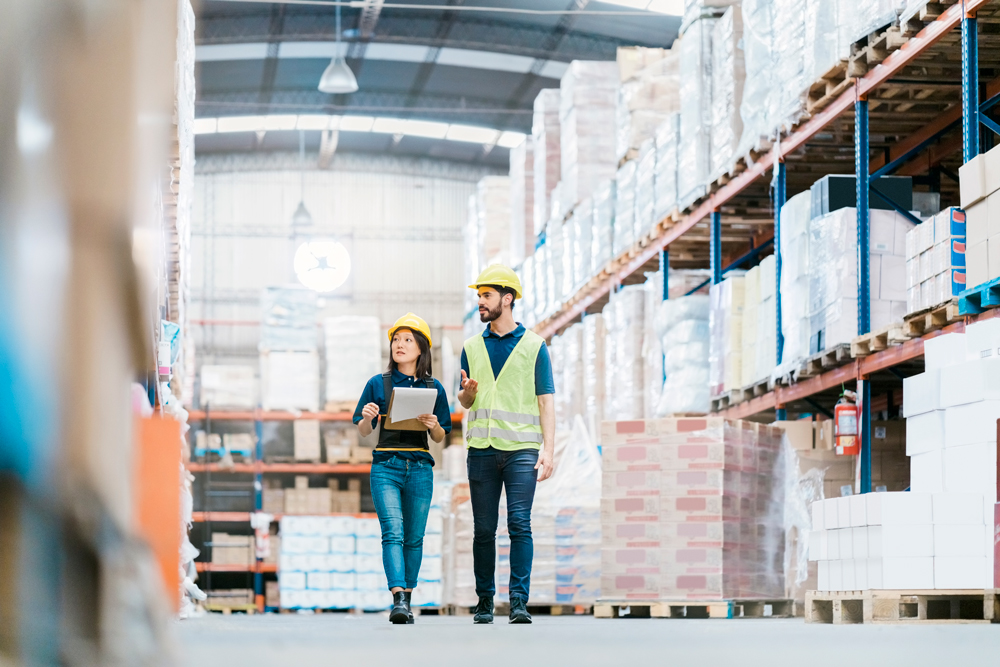 Two construction workers walking and chatting while looking at inventory.