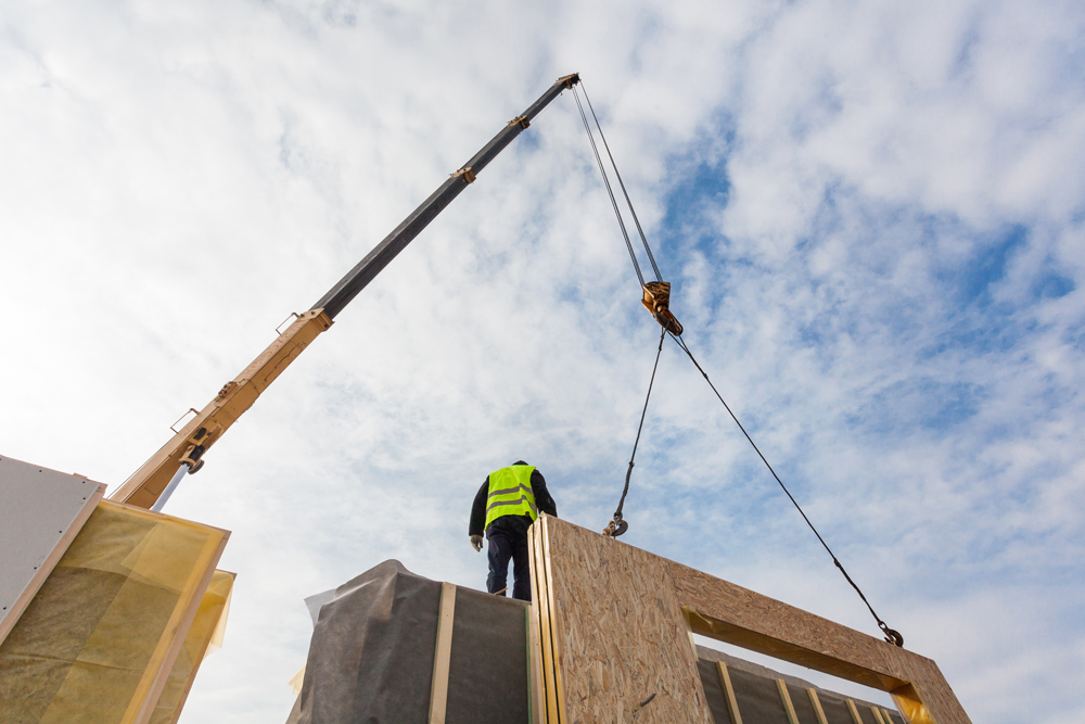 man construction worker on top of unfinished building structure.