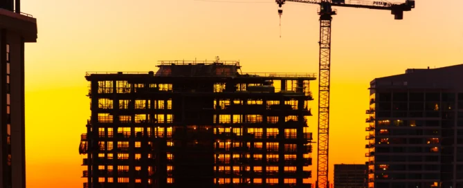 Silhouette Of Crane And Building Under Construction At Dusk.
