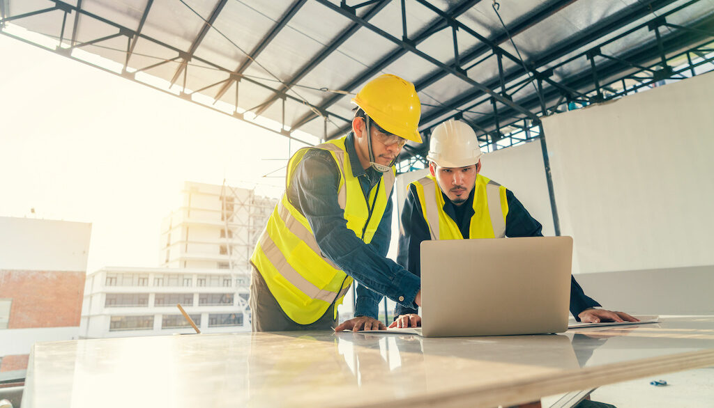 Asian Man Civil Engineer And Contractor Working With Computer Laptop On The Table In Construction Site. Asian Man Civil Engineer And Contractor Working With Computer Laptop On The Table In Construction Site.